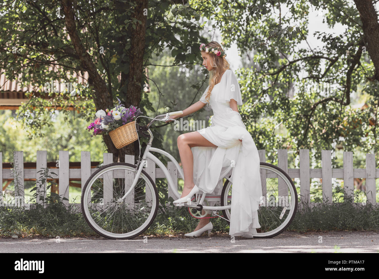 Seite Blick auf die schöne junge Braut im Brautkleid Reiten Fahrrad- und weg schauen Stockfoto