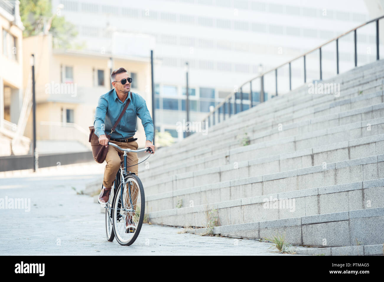 Stattlich im mittleren Alter Geschäftsmann in Sonnenbrille Reiten Fahrrad und Weg schauen auf der Straße Stockfoto