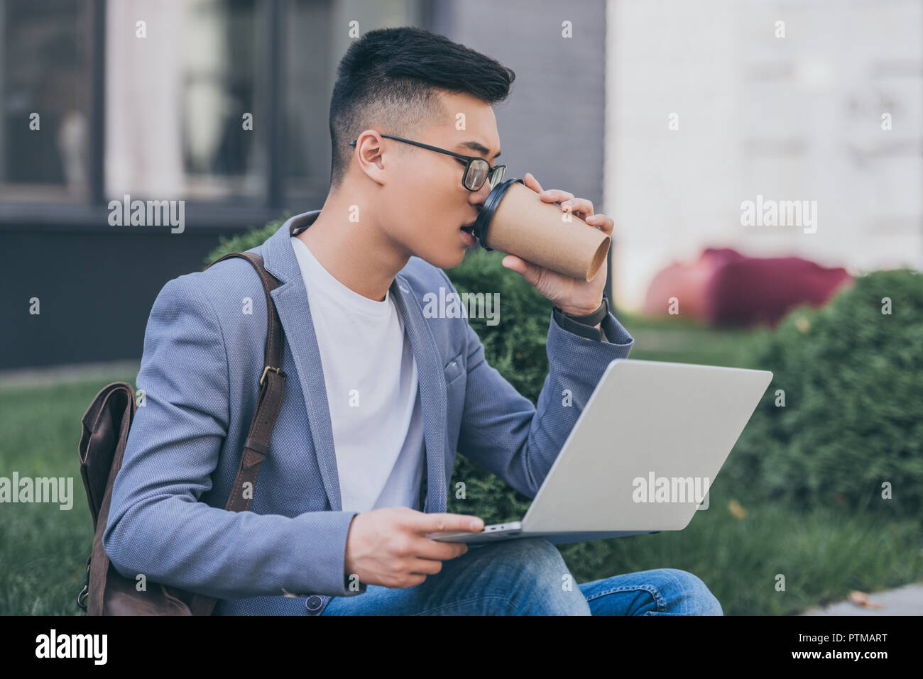 Schönen asiatischen Freiberufler Kaffee trinken zu gehen und Arbeiten am Laptop sitzend auf Bürgersteig Stockfoto