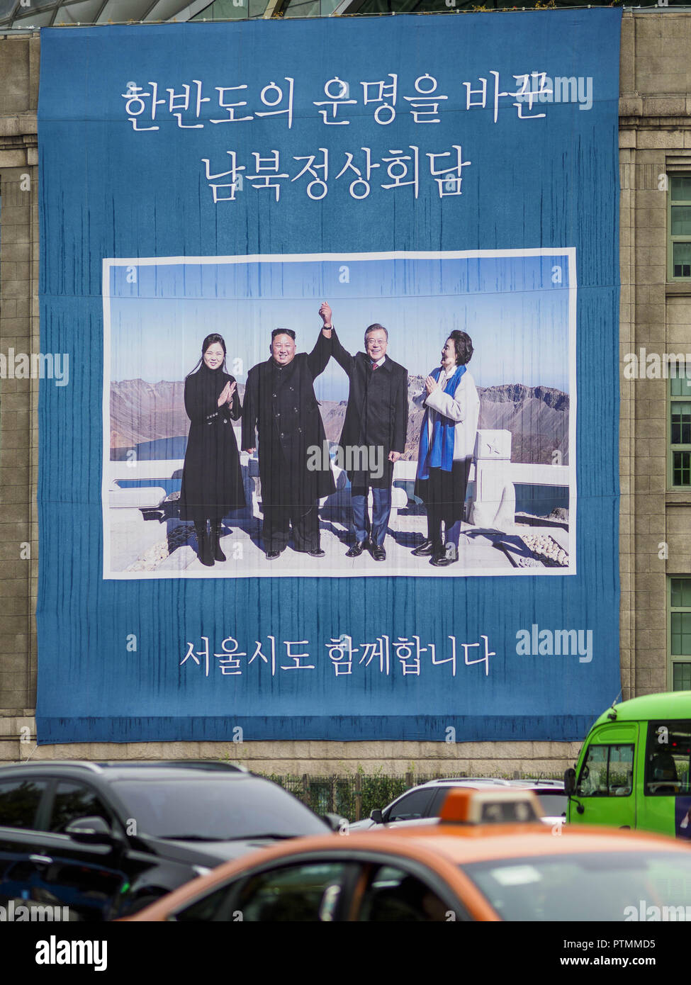 Seoul, Europa, Deutschland, Baden-Württemberg, Südkorea. 9. Okt., 2018. Verkehr auf Sejong-Daero Straße führt vorbei an einem großen Schild hängen von der Seoul öffentliche Bibliothek Kennzeichnung der September Gipfeltreffen zwischen Nord Koreanischen führen Kim Jong-un (Mitte links) und seine Frau, Ri Sol-ju (links) und südkoreanischen Präsidenten Moon Jae-in (Mitte rechts) und seine Frau, Kim Jung-sook. Credit: Jack Kurtz/ZUMA Draht/Alamy leben Nachrichten Stockfoto