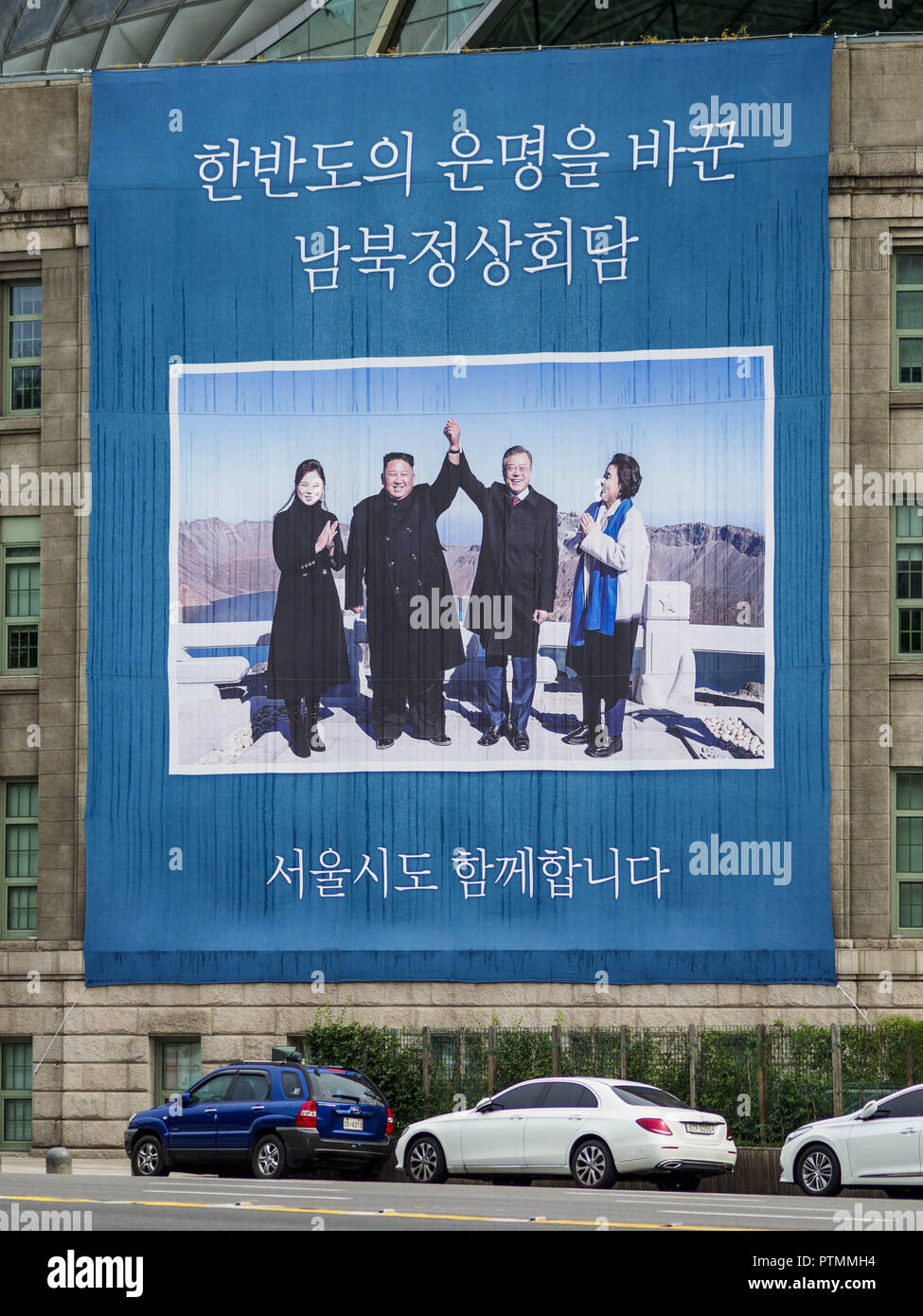 Seoul, Europa, Deutschland, Baden-Württemberg, Südkorea. 9. Okt., 2018. Verkehr auf Sejong-Daero Straße führt vorbei an einem großen Schild hängen von der Seoul öffentliche Bibliothek Kennzeichnung der September Gipfeltreffen zwischen Nord Koreanischen führen Kim Jong-un (Mitte links) und seine Frau, Ri Sol-ju (links) und südkoreanischen Präsidenten Moon Jae-in (Mitte rechts) und seine Frau, Kim Jung-sook. Credit: Jack Kurtz/ZUMA Draht/Alamy leben Nachrichten Stockfoto