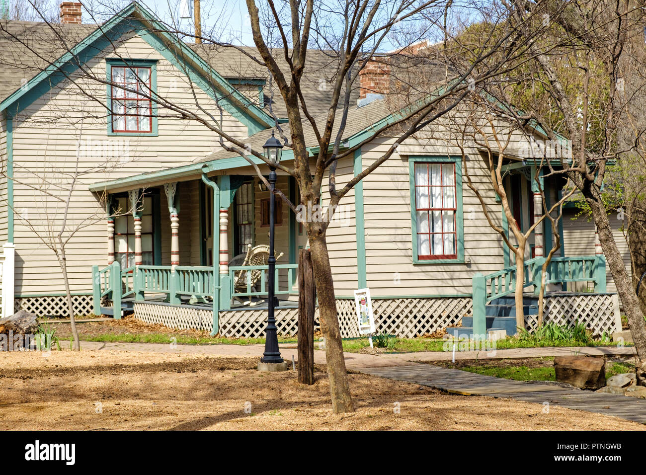 Weiß geschuppt altes Haus mit blauem Trimm. Bäume, horizontal. Die dulaney Cottage, Kastanie Square Historic Village, McKinney, Texas. Stockfoto
