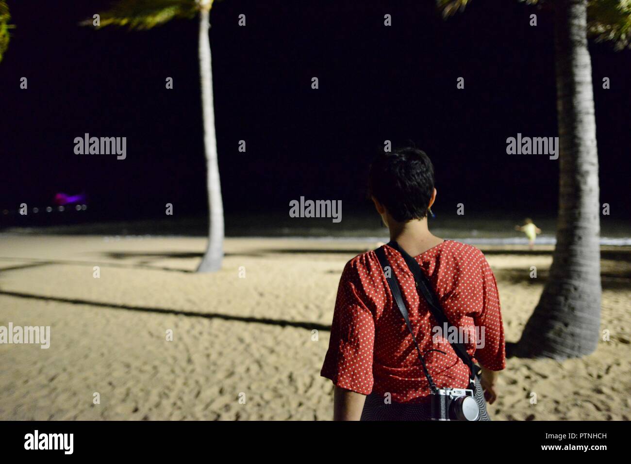 Eine Frau Spaziergänge am Strand bei Nacht, Townsville, Queensland, Australien Stockfoto