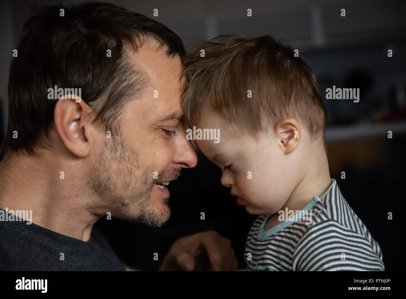 Süße Junge mit Down-syndrom spielen mit Vati auf der Startseite Stockfoto