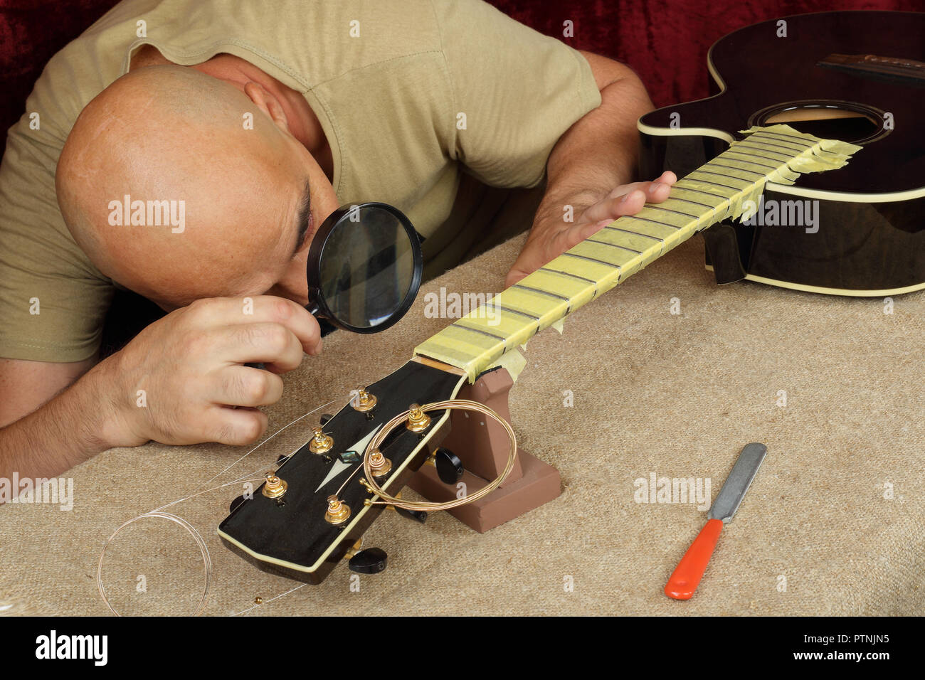 Musical Instrument Gitarre Reparatur und Service Mitarbeiter Kontrolle schärfen Spezialwerkzeug Brücke servo Mutter schwarz akustische Gitarre Stockfoto