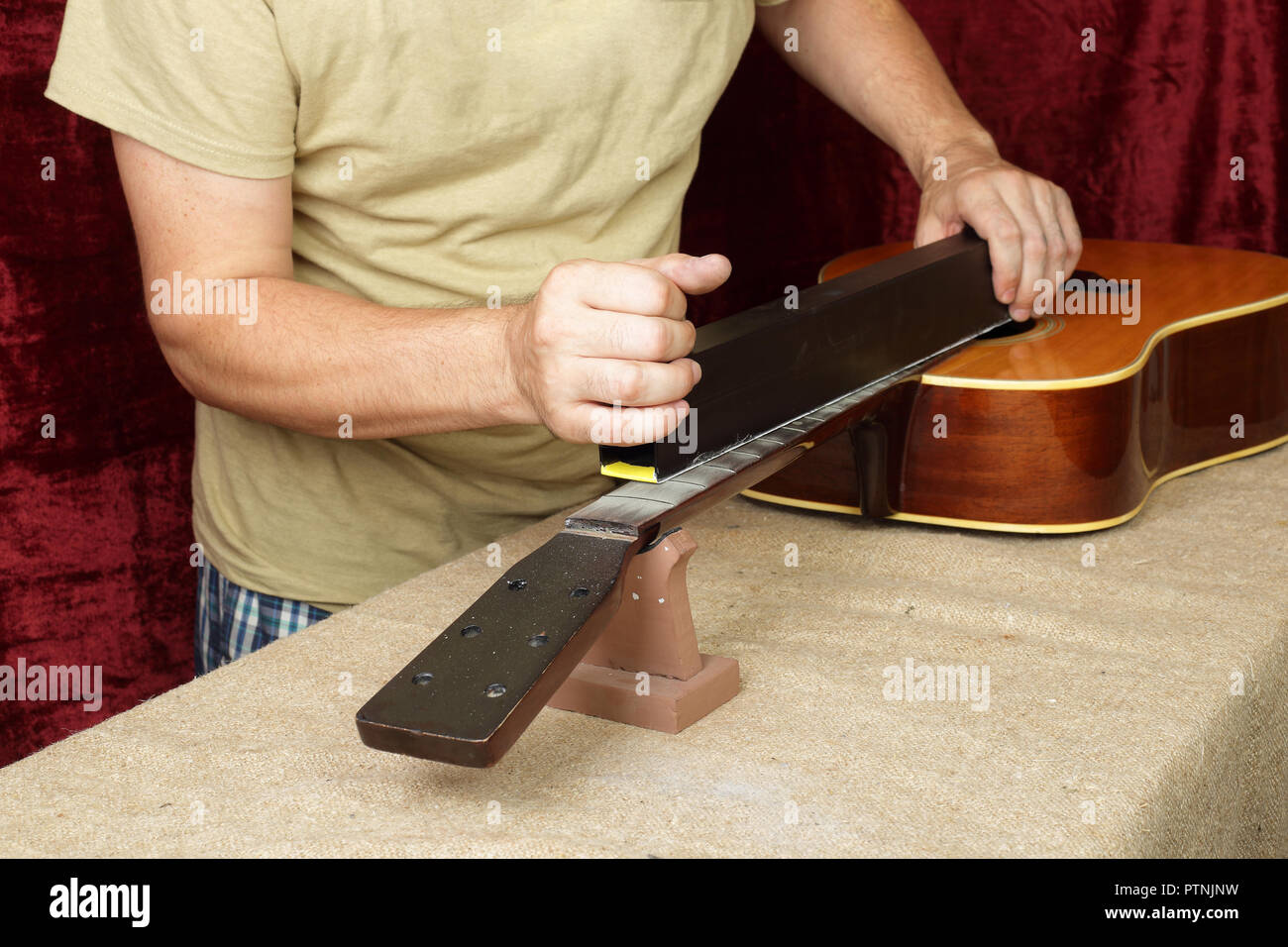 Musical Instrument Gitarre Reparatur und Service Mitarbeiter schleift nat Holz Gitarre Hals Bünde. Stockfoto