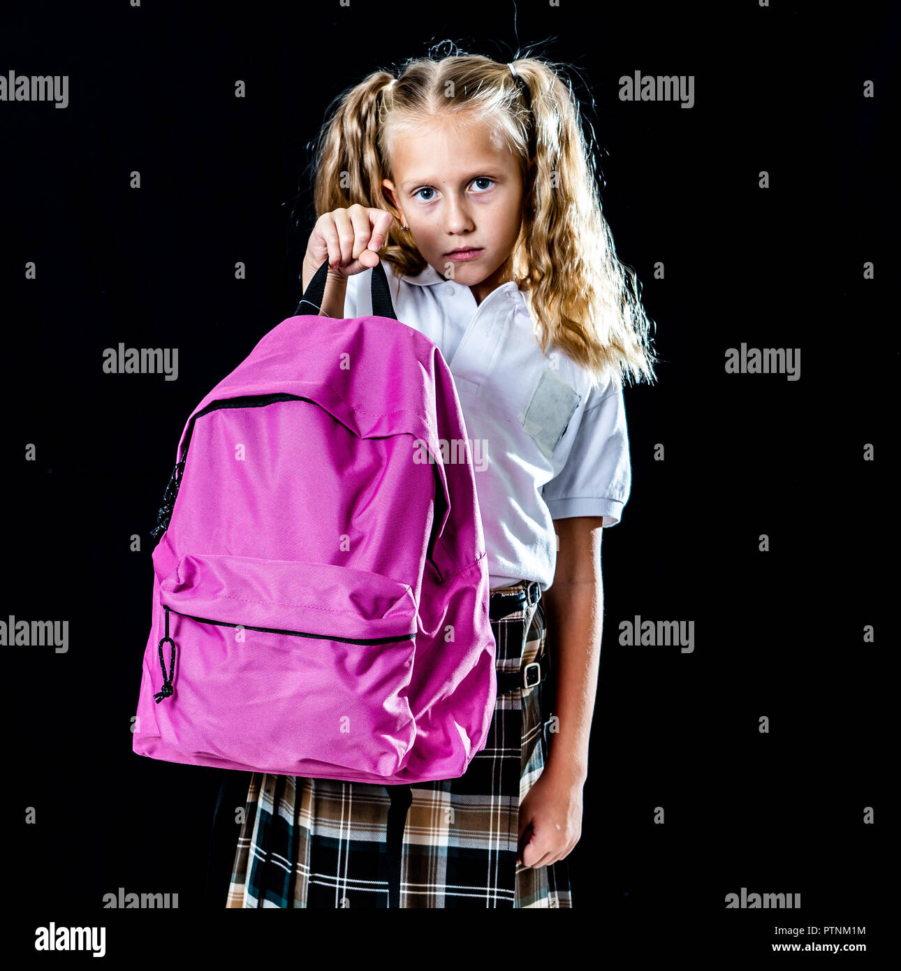 Unglücklich school girl Holding a big Schultasche voller Bücher und Heimarbeit auf schwarzen Hintergrund in Zurück isolierte Schwierigkeiten lernen Hausaufgaben in die Schule ein Stockfoto