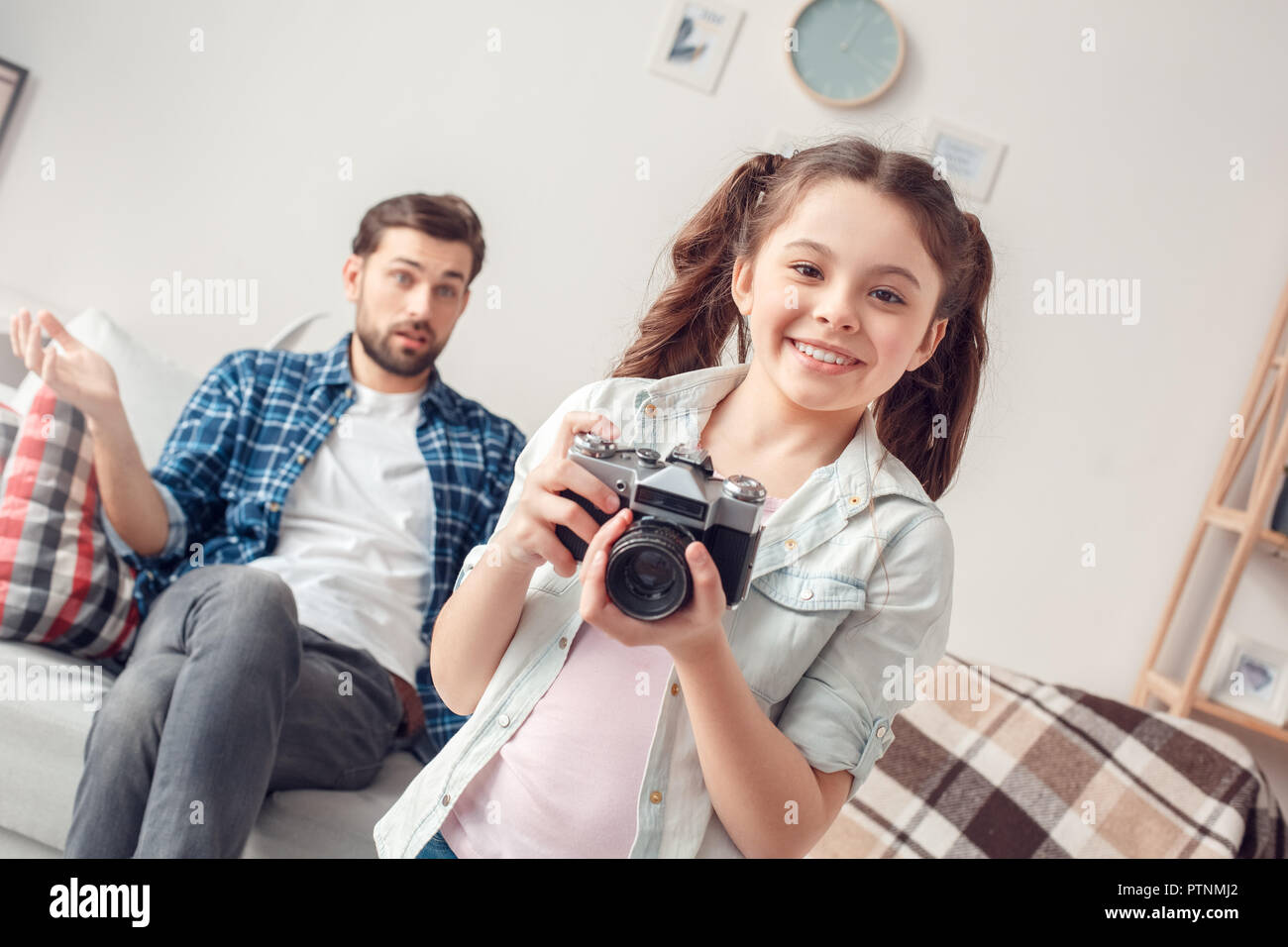 Bärtiger Mann und kleine Mädchen zu Hause Familie Zeit Tochter ständigen Holding Kamera fotografieren Lachen auf photographere neugierig, während fathe Stockfoto