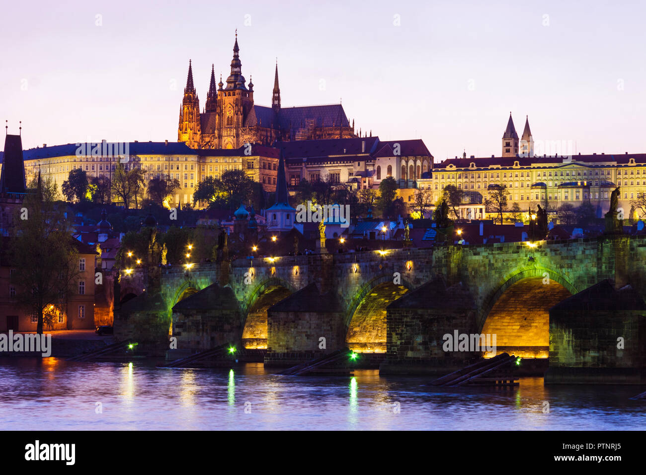 Prag, Tschechische Republik: Karlsbrücke, Veitsdom und Prager Burgkomplex leuchtet in der Dämmerung. Stockfoto