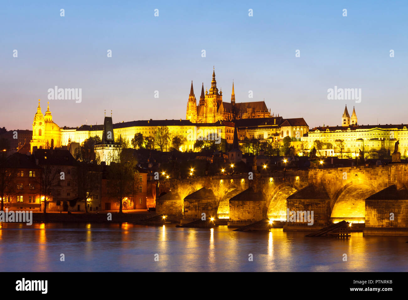 Prag, Tschechische Republik: Karlsbrücke, Veitsdom und Prager Burgkomplex leuchtet in der Dämmerung. Stockfoto