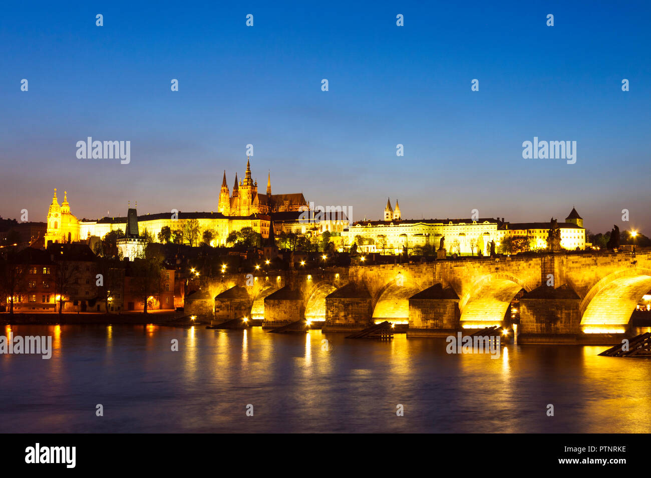 Prag, Tschechische Republik: Karlsbrücke, Veitsdom und Prager Burgkomplex leuchtet in der Dämmerung. Stockfoto