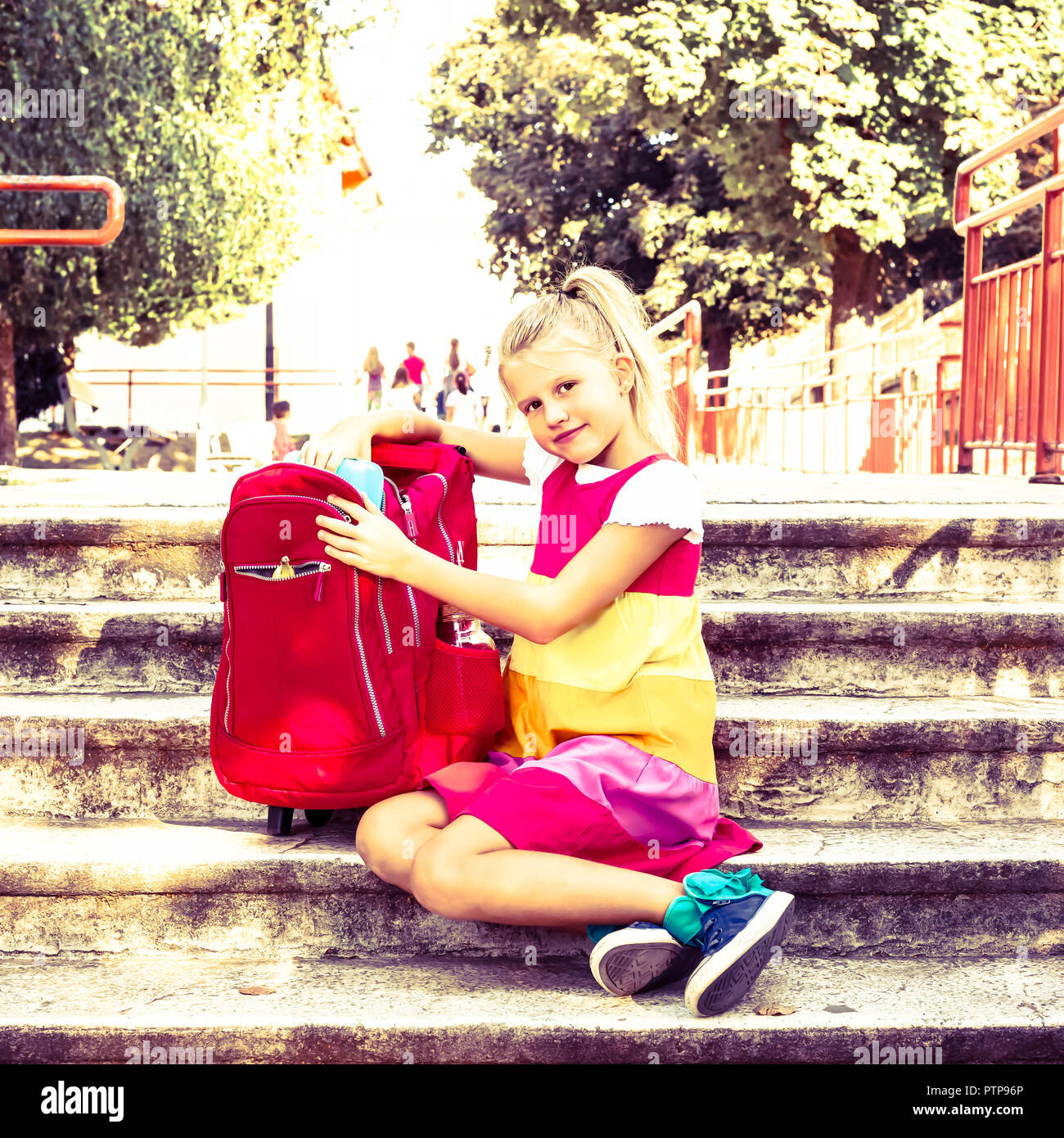 Happy School Girl herausziehen Lunchbox aus ihrem Rucksack auf dem Schulhof - Mittagspause Stockfoto