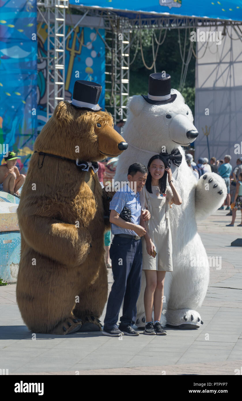 Wladiwostok, Russia-July 28, 2018: Portrait von asiatischen Touristen auf dem Hintergrund von Leuten in Kostümen von hohen Bären gekleidet. Stockfoto