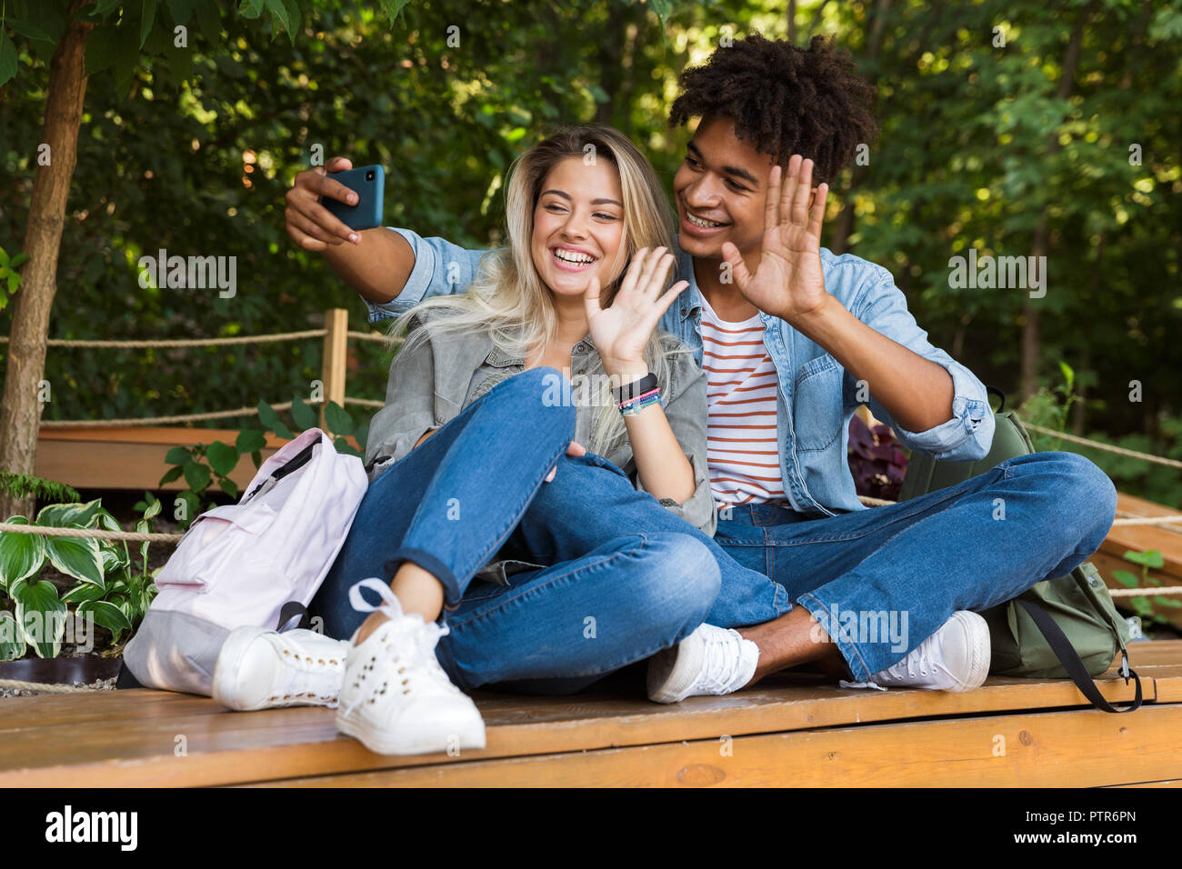 Jungen multiethnischen Ehepaar miteinander reden, während die Zeit zusammen im Park begeistert, wobei ein selfie, winken mit Händen Stockfoto
