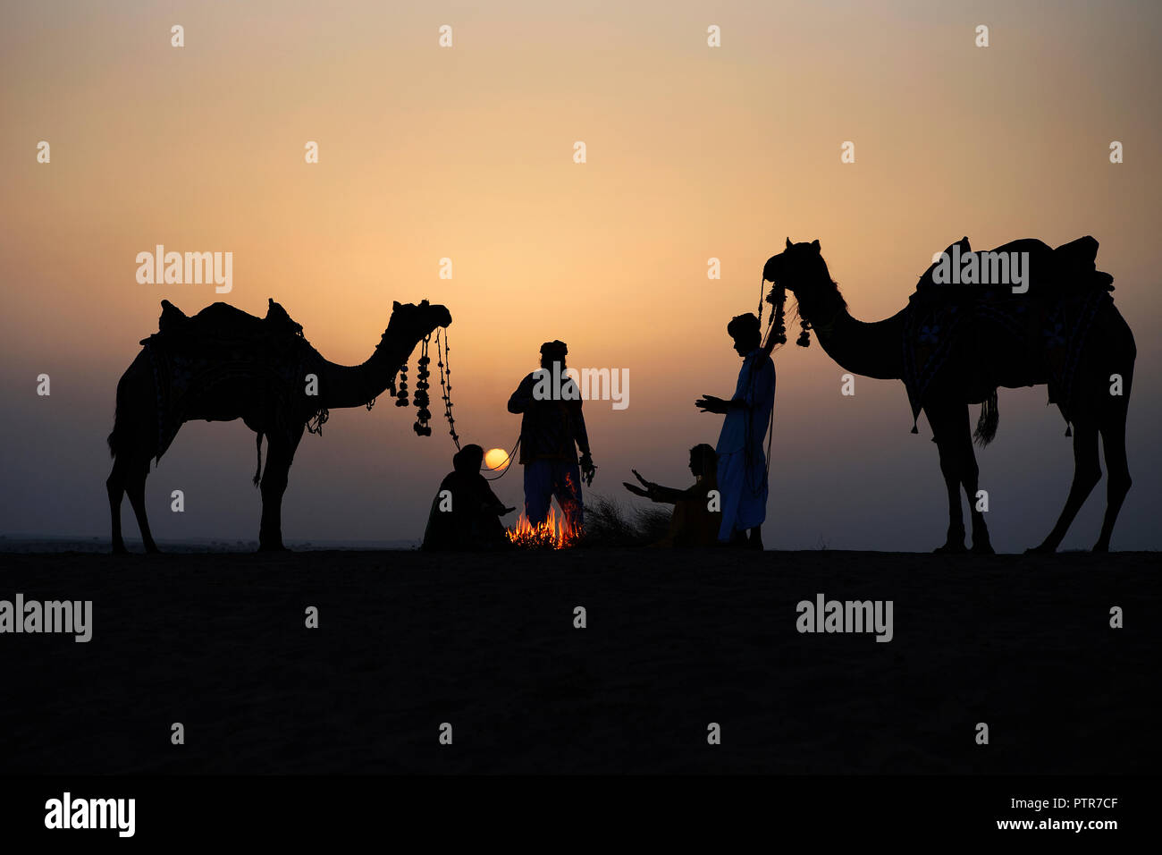 Das Bild der Rajasthani aus massivem Messing Mann, Frauen und Kamel mit Feuer bei Sonnenaufgang in Jaisalmer, Rajasthan, Indien Stockfoto