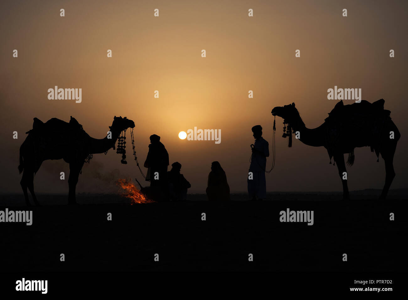 Das Bild der Rajasthani aus massivem Messing Mann, Frauen und Kamel mit Feuer bei Sonnenaufgang in Jaisalmer, Rajasthan, Indien Stockfoto