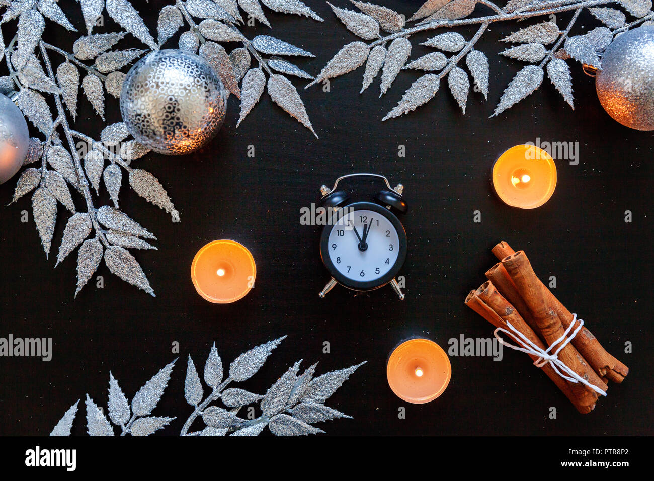 Weihnachten Neujahr Zusammensetzung winter Objekte Kerze, Uhr silber Zweig, Kugeln und Bälle auf dunklen schwarzen Hintergrund. Flach, Ansicht von oben, kopieren. Stockfoto