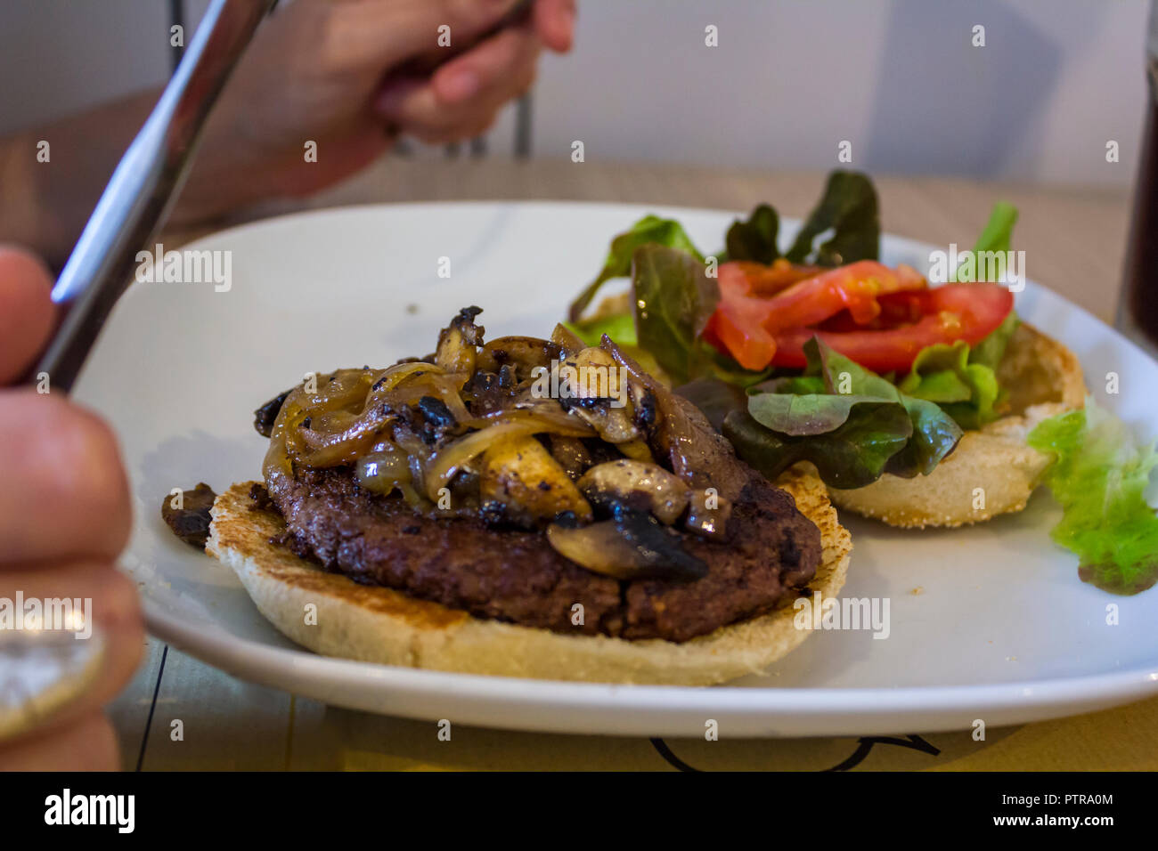 Ein Hamburger auf dem Teller Essen mit Besteck Stockfotografie - Alamy