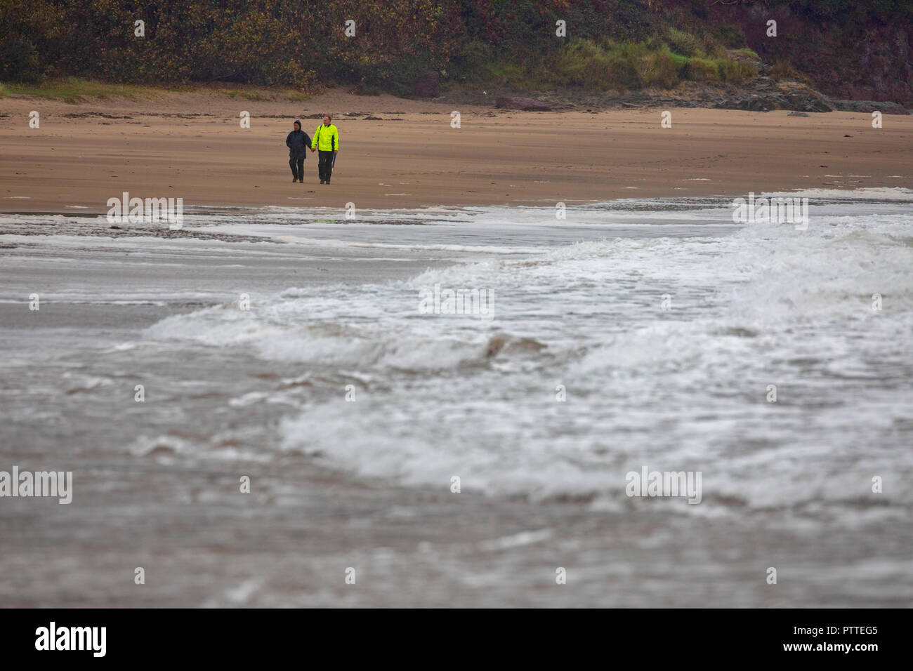 Süßwasser-Ost, Pembrokeshire, Wales, 11 Uhr Oktober 2018. UK Wetter: Nass stürmisches Wetter beginnt für schwere See mit Sturm Callum bilden für eine stürmische Wochenende voran Pembrokeshire, Wales zu machen. Ein paar Mutige die nassen und windigen Wetter für einen Spaziergang entlang der Küste, wie Wellen in das Ufer, Süßwasser-Ost, Pembrokeshire © DGDImages/AlamyNews Stockfoto