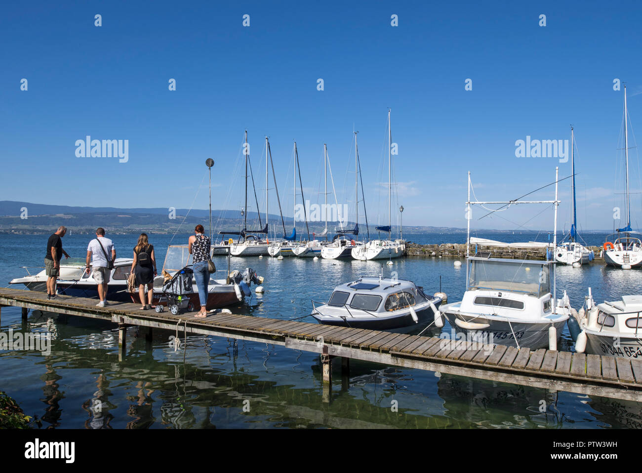 Touristen, die auf der Suche nach Motorboote und Segelboote im Hafen festgemacht an Yvoire entlang dem Genfer See/Lac Léman, Haute-Savoie, Frankreich Stockfoto