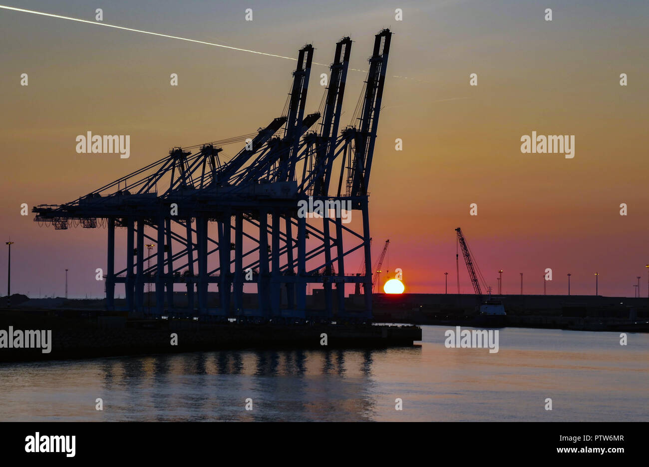 Krane und Boot in den Hafen, Hafen, von der Fähre bei Sonnenuntergang gesehen, Zeebrugge Hafen, Belgien, Stockfoto