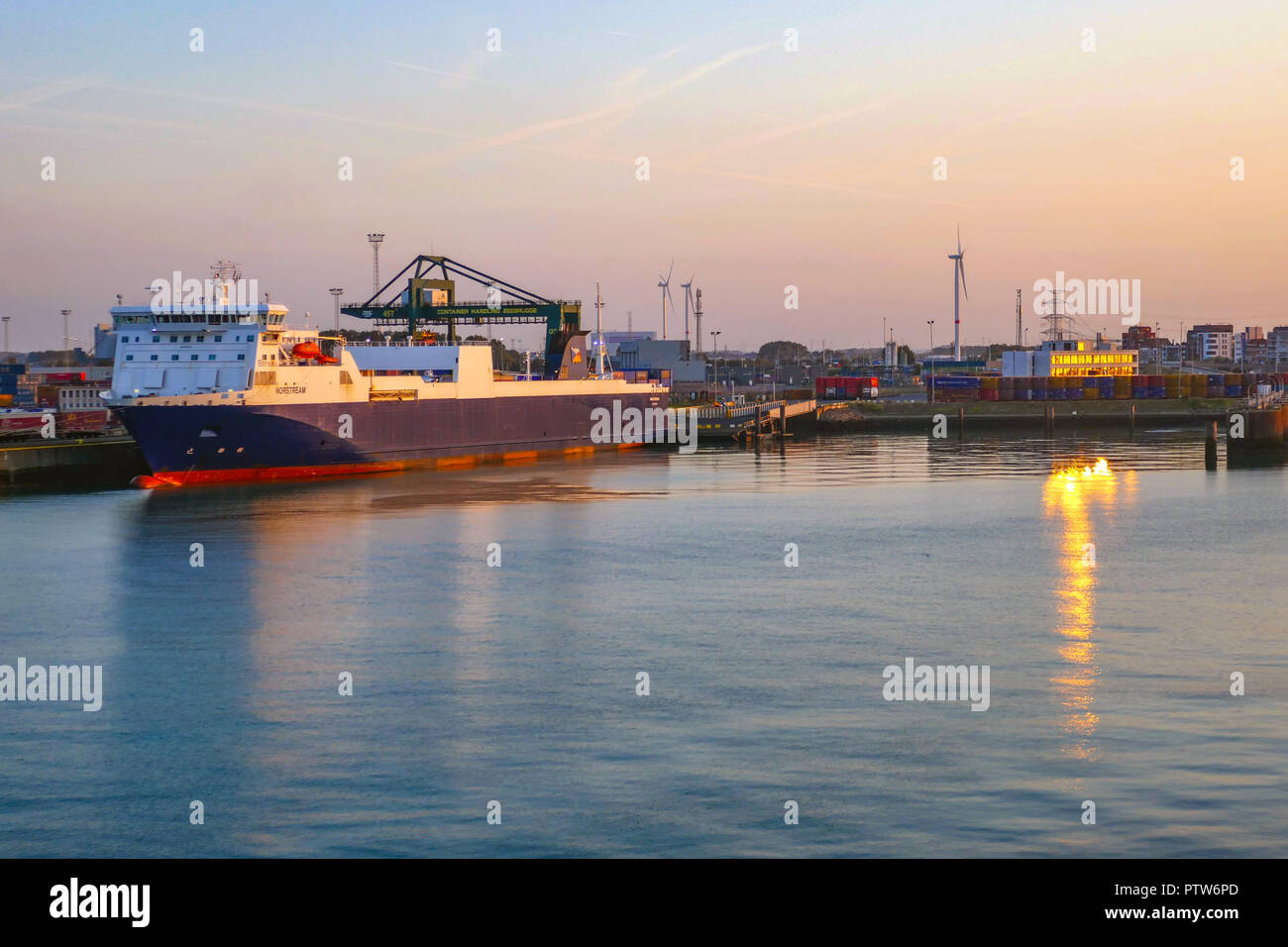 Krane und Boot in den Hafen, Hafen, von der Fähre bei Sonnenuntergang gesehen, Zeebrugge Hafen, Belgien, Stockfoto