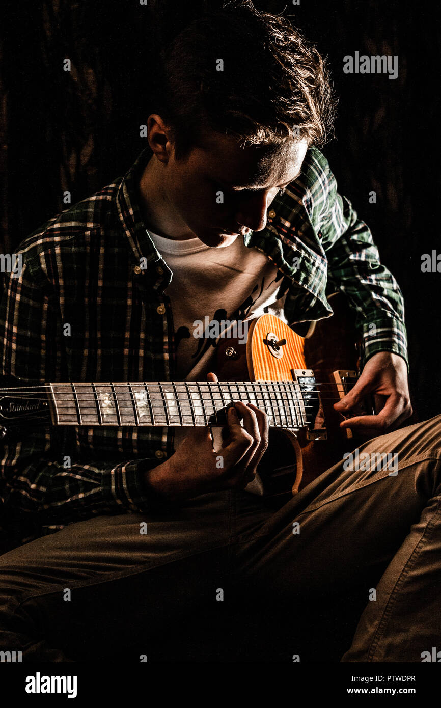 Linkshänder Männliche Jugendlich Musiker spielt E-Gitarre, mit ihm auf seinen Schoß. Stockfoto