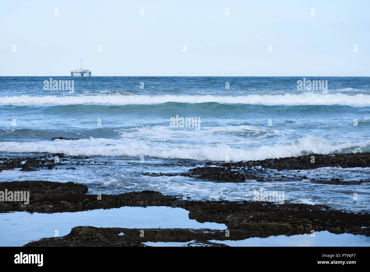 Rock Pools am Meer mit Ozean Horizont und Öl Bohrinsel in der Ferne Stockfoto
