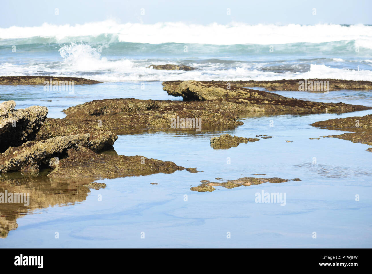 Klaren ruhigen Ozean Rock Pools mit rauhen Wellen Anfahren Stockfoto