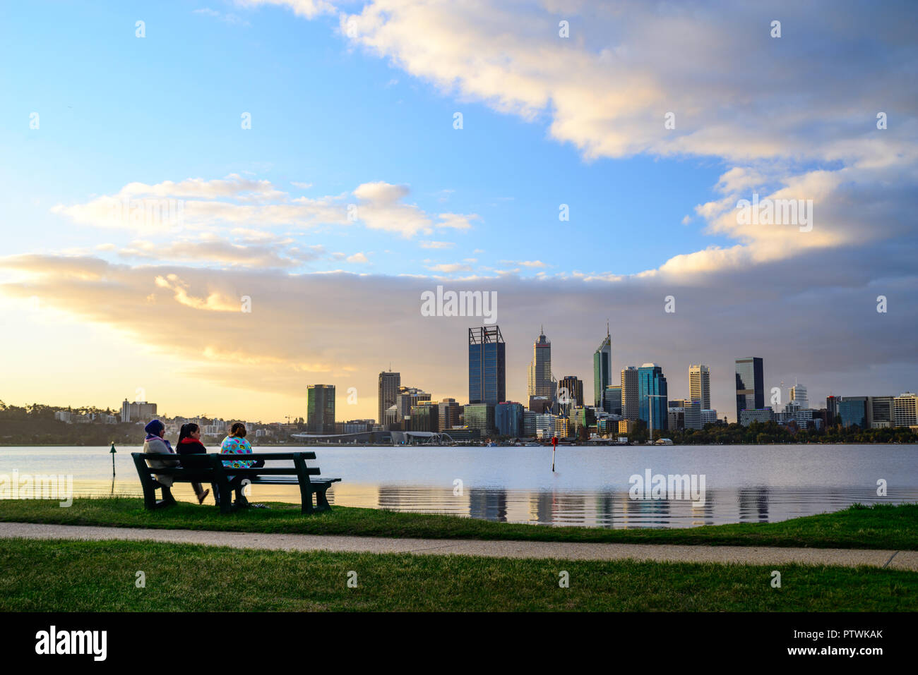 3 Personen auf einer Bank vor der Skyline von Perth mit Swan River. Ansicht von Süden Perth, Perth, Western Australia Stockfoto