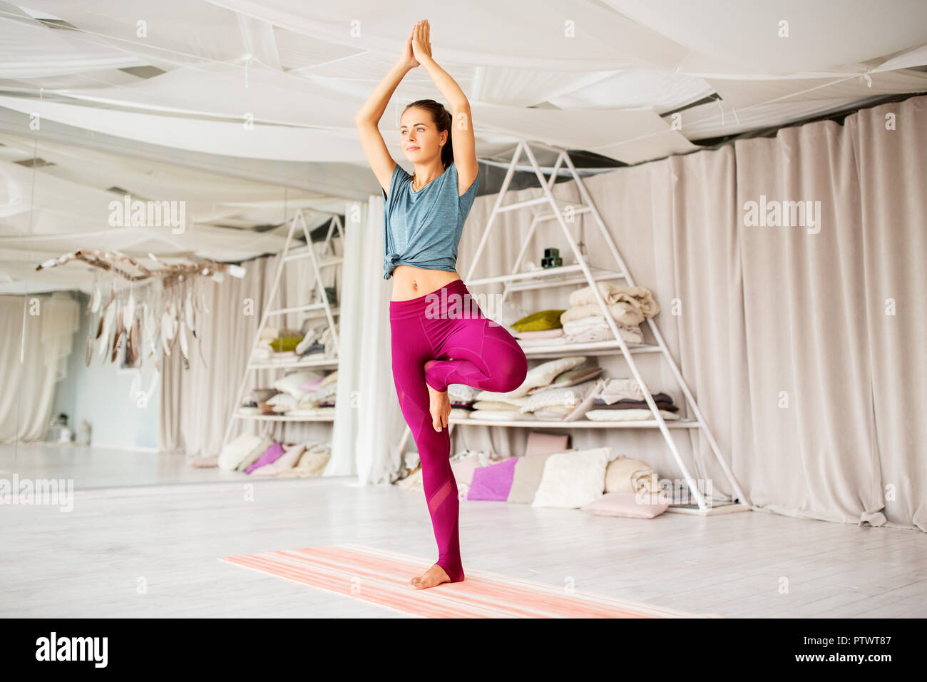 junge Frau tut Yoga-Baum-Pose im studio Stockfoto