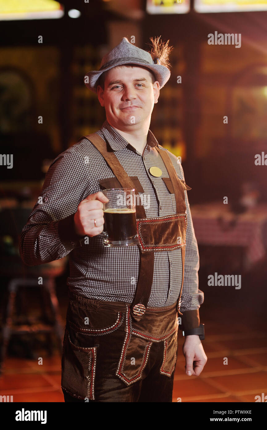 Mann in Traditionelle bayerische Kleidung auf dem Oktoberfest mit einem Bier in der Hand, Lächeln auf dem Hintergrund der Pub Stockfoto