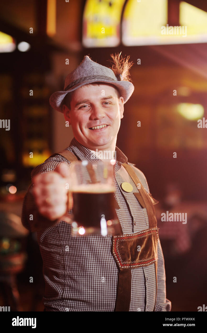 Mann in Traditionelle bayerische Kleidung auf dem Oktoberfest mit einem Bier in der Hand, Lächeln auf dem Hintergrund der Pub Stockfoto