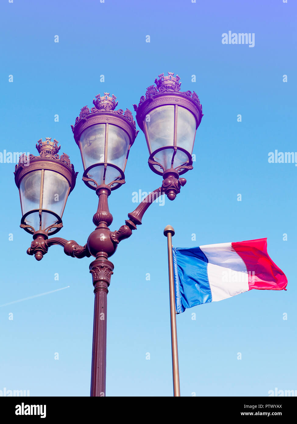 Typische Laterne von Paris und französischen Fähnchen im Wind vor einem blauen Himmel Stockfoto