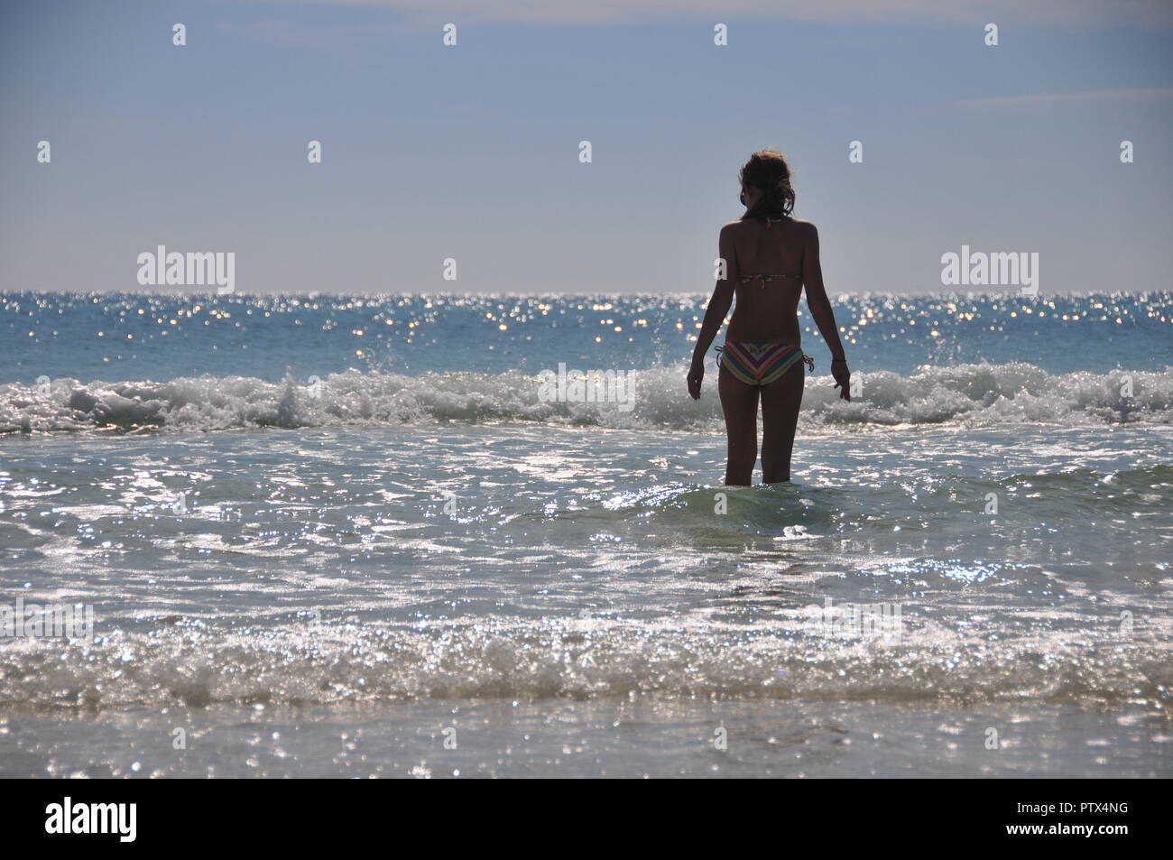 Mädchen im Bikini zu Fuß in die Wellen Silhouette Stockfoto