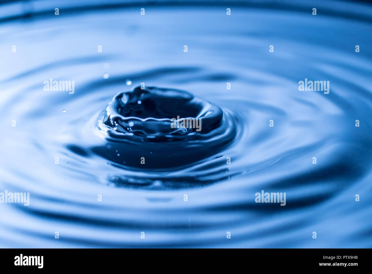 Wassertropfen spritzen in einem Glas blau Stockfoto