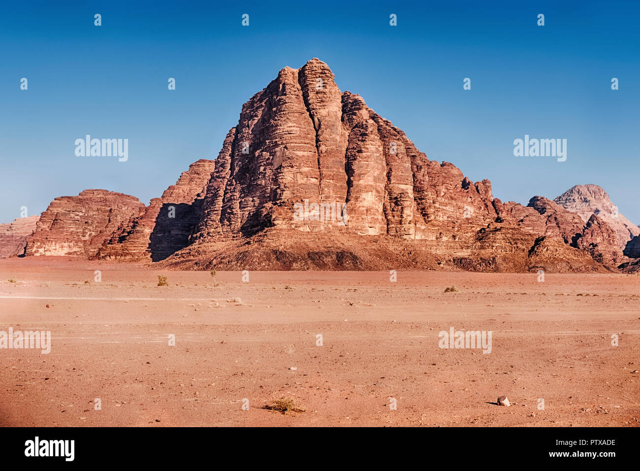 Im Wadi Rum Wüste im südlichen Jordanien, die Landschaft wird durch die Klippen und Strebepfeiler der Berg der sieben Säulen dominiert. Stockfoto
