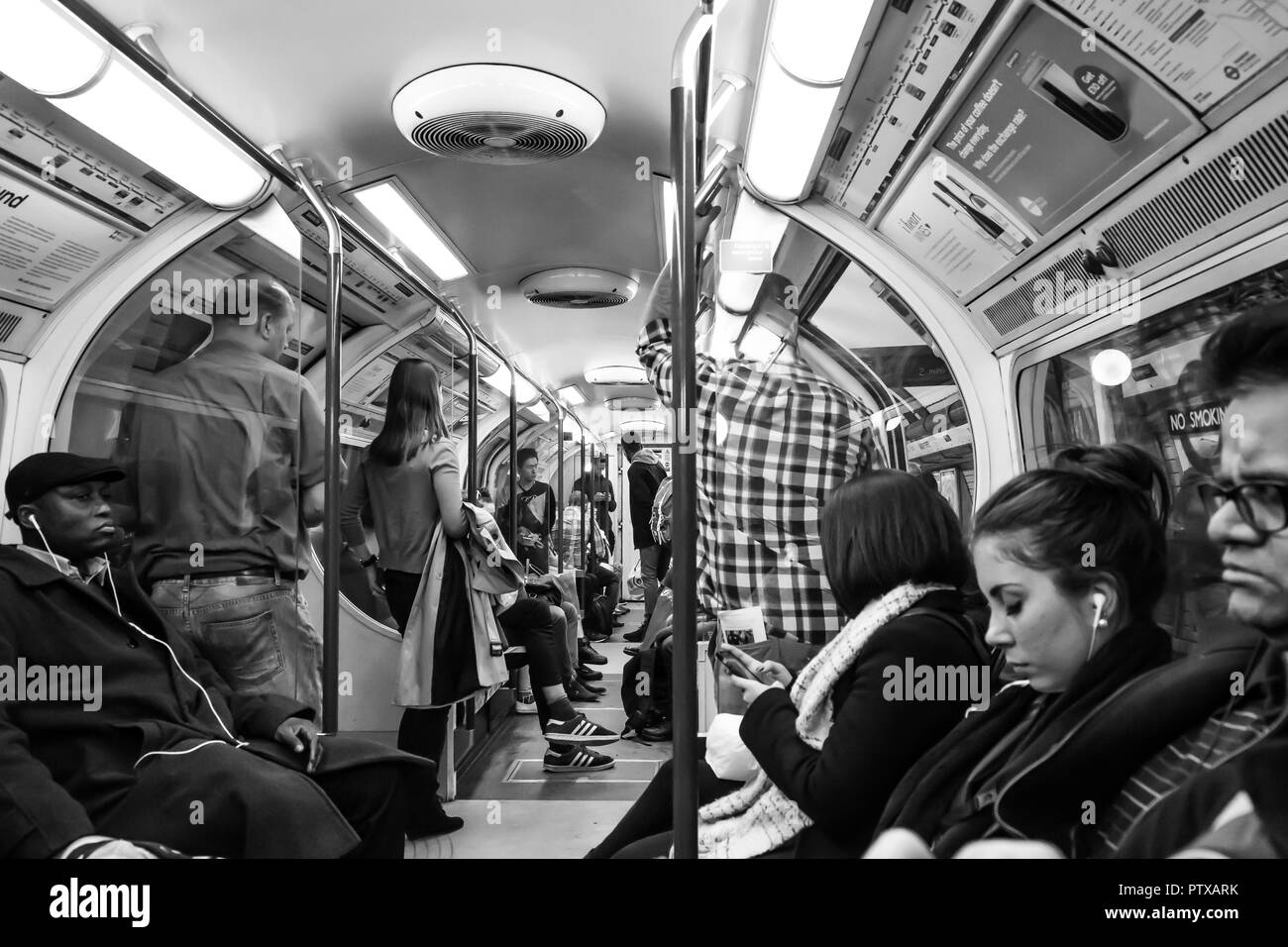 Schwarz & Weiß, Natur schoss der Passagiere bei London Rohr, Innen besetzt Waggon; miserable Pendler Stehen und Sitzen, keine Interaktion. Stockfoto