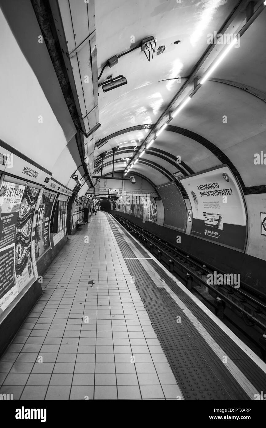 London Tube Station; Schwarz & Weiß Schuß von verlassenen Plattform/rail line in der Londoner U-Bahnstation Marylebone. Einsame Figur wartet im Abstand. Stockfoto