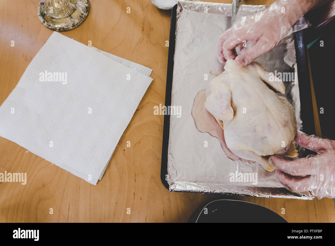 Ganze rohe Huhn, spatchcocked in Vorbereitung auf die Röstung: Hände schließen sich das Tragen der Umgang mit Lebensmitteln und Handschuhe mit Messer und Schere Stockfoto