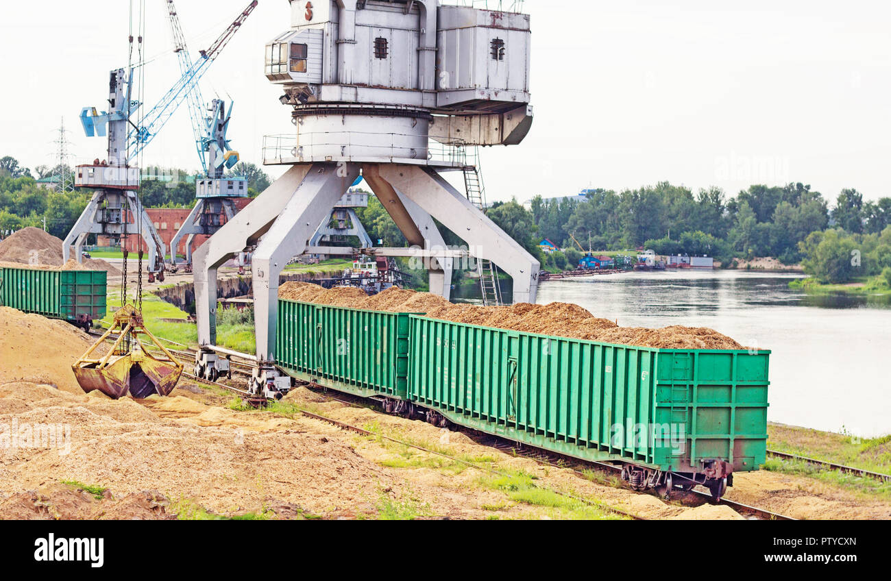 Der Hafenkran macht das Laden der Späne in die Güterwagen der Bahn, laden Stockfoto