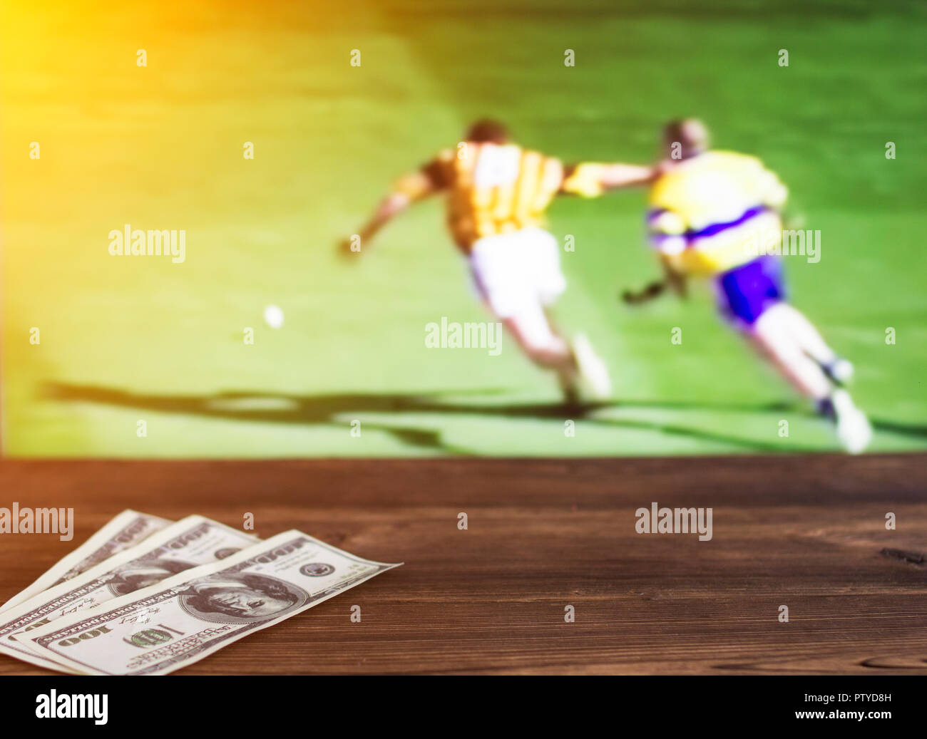 Geld Dollar auf dem Hintergrund einer TV, auf dem der Sport im Spiel von hurling gezeigt wird, Sportwetten, Dollar Stockfoto