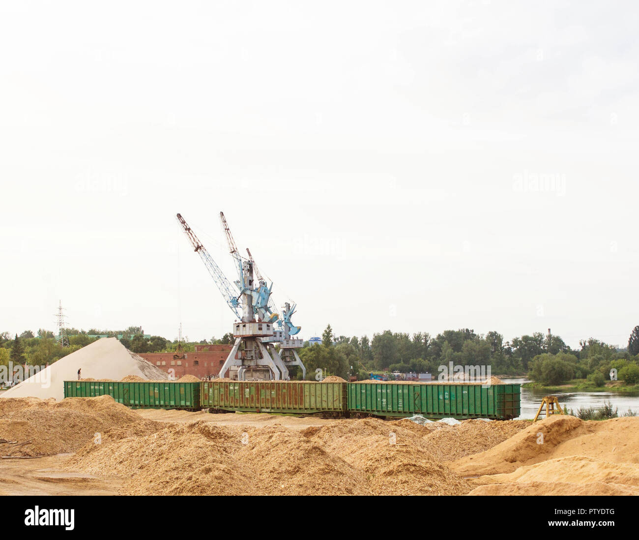 Der Hafenkran macht das Laden der Späne in die Güterwagen der Bahn, laden Stockfoto