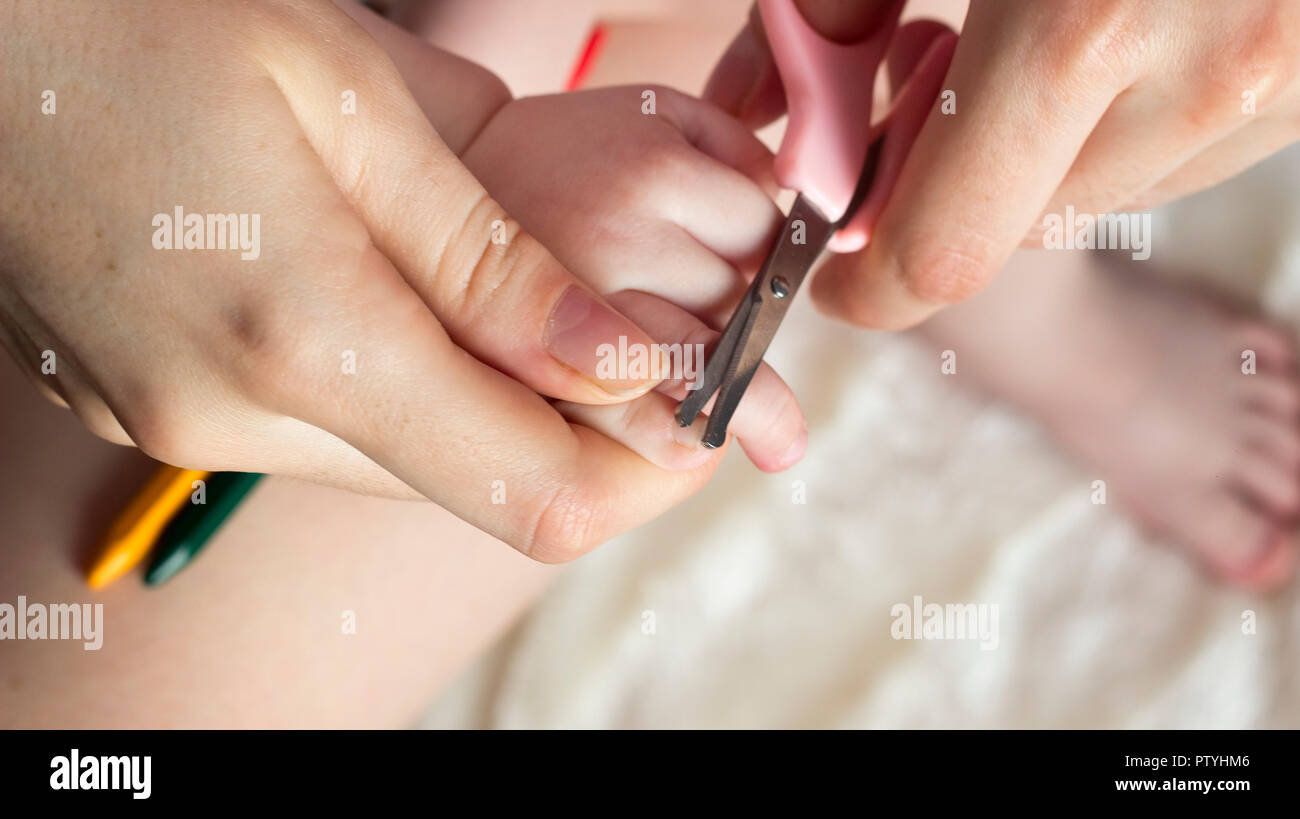 Mutter schneidet sich die Nägel in den Händen eines kleinen Mädchens, close-up Stockfoto