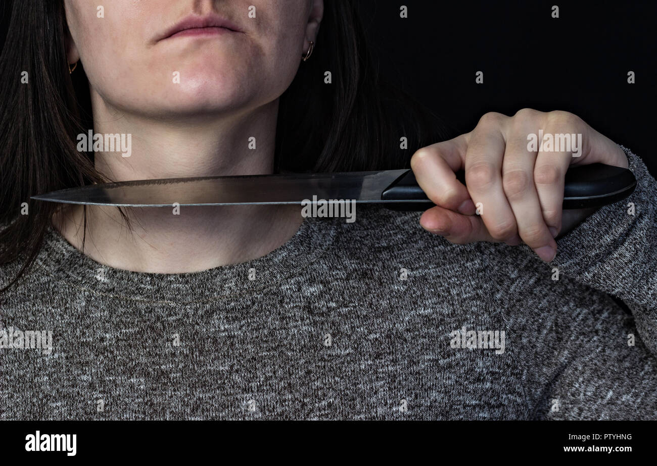 Mädchen bringt Messer an ihre Kehle, schwarzer Hintergrund Stockfoto