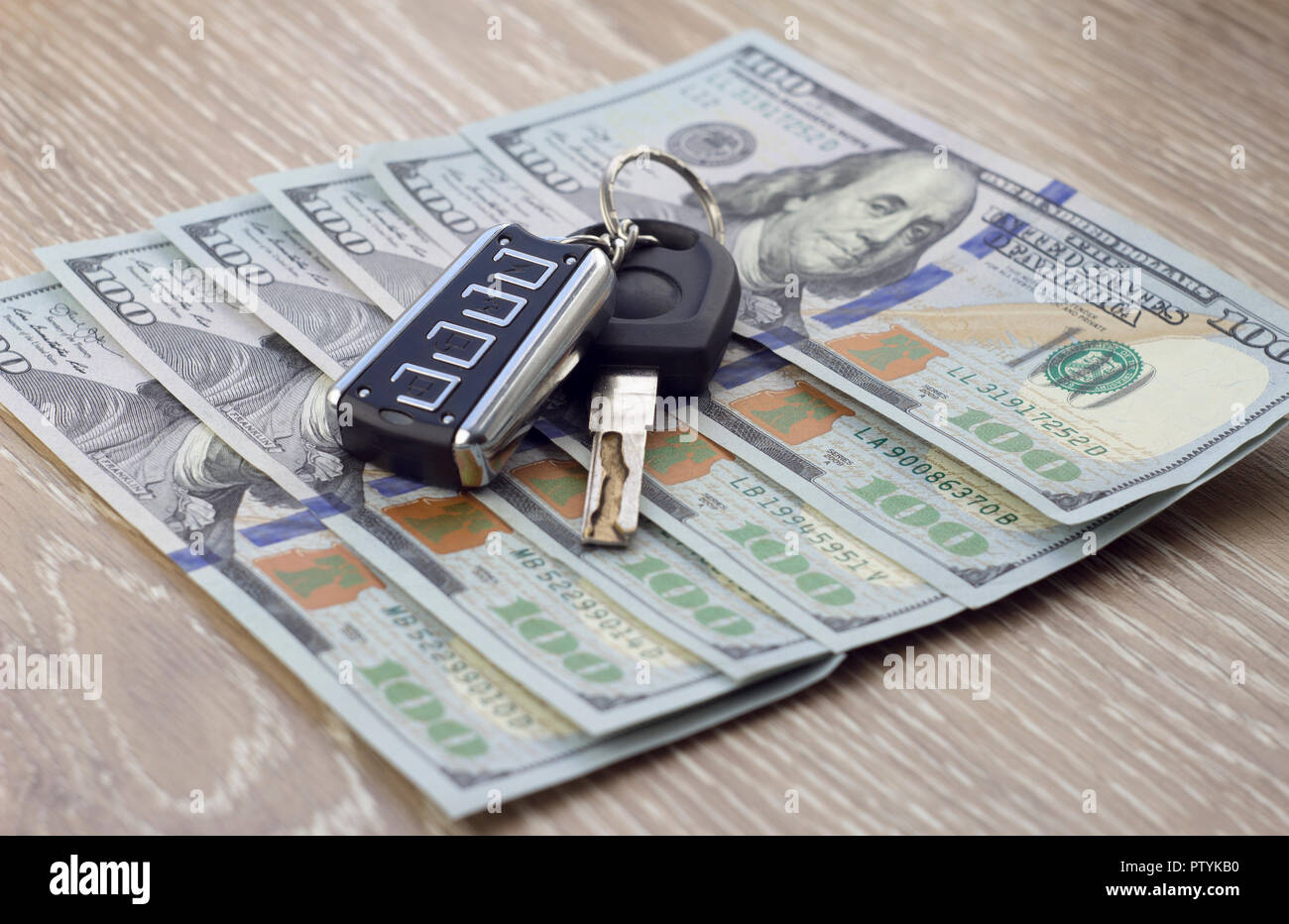 Autoschlüssel und Geld Dollar auf einem hölzernen Hintergrund Stockfoto