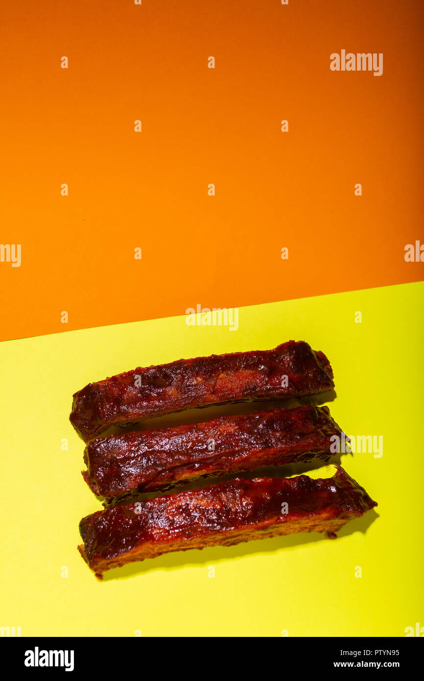 Gegrillt und mariniert klebrige Spare Ribs auf gelb und orange Hintergrund mit kopieren. Stockfoto