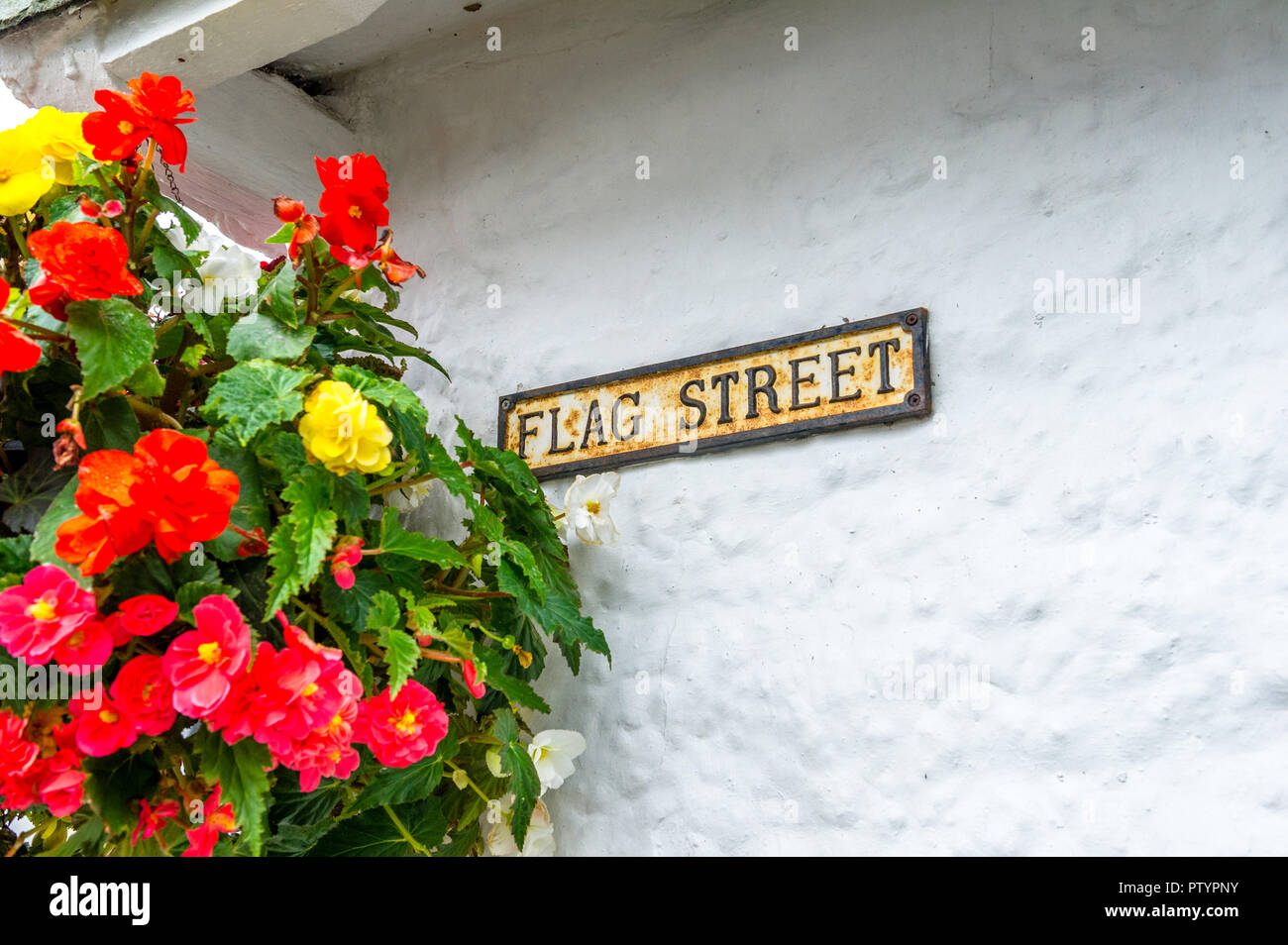 Reihe von blumenampeln entlang der weißen Häusern und engen Gassen in Hawkshead, Windermere, Cumbria gewaschen. Stockfoto