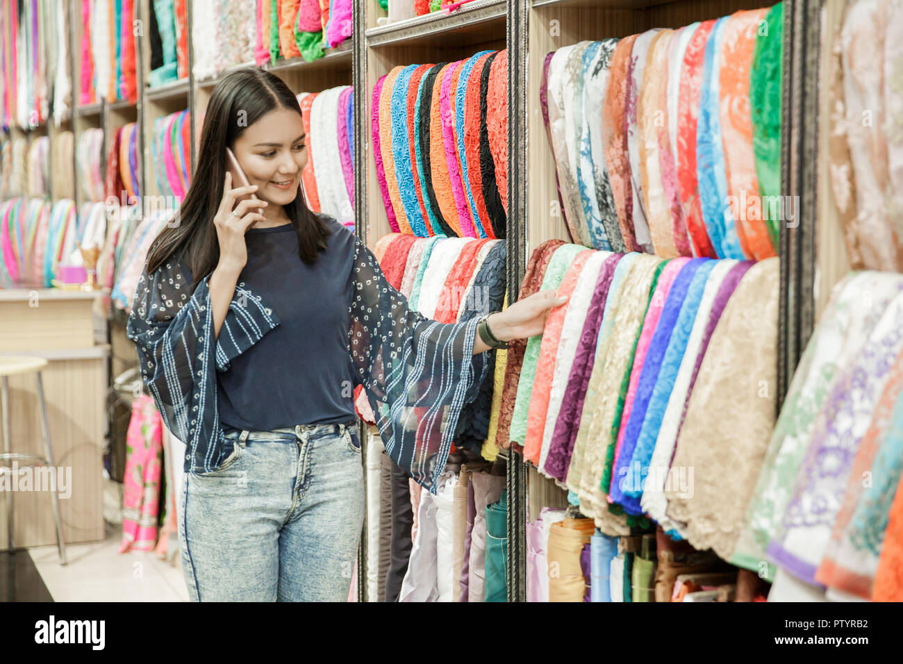 Porträt der schönen Frau Gespräch am Handy während der Suche um Stoffe bei Fabric store Stockfoto