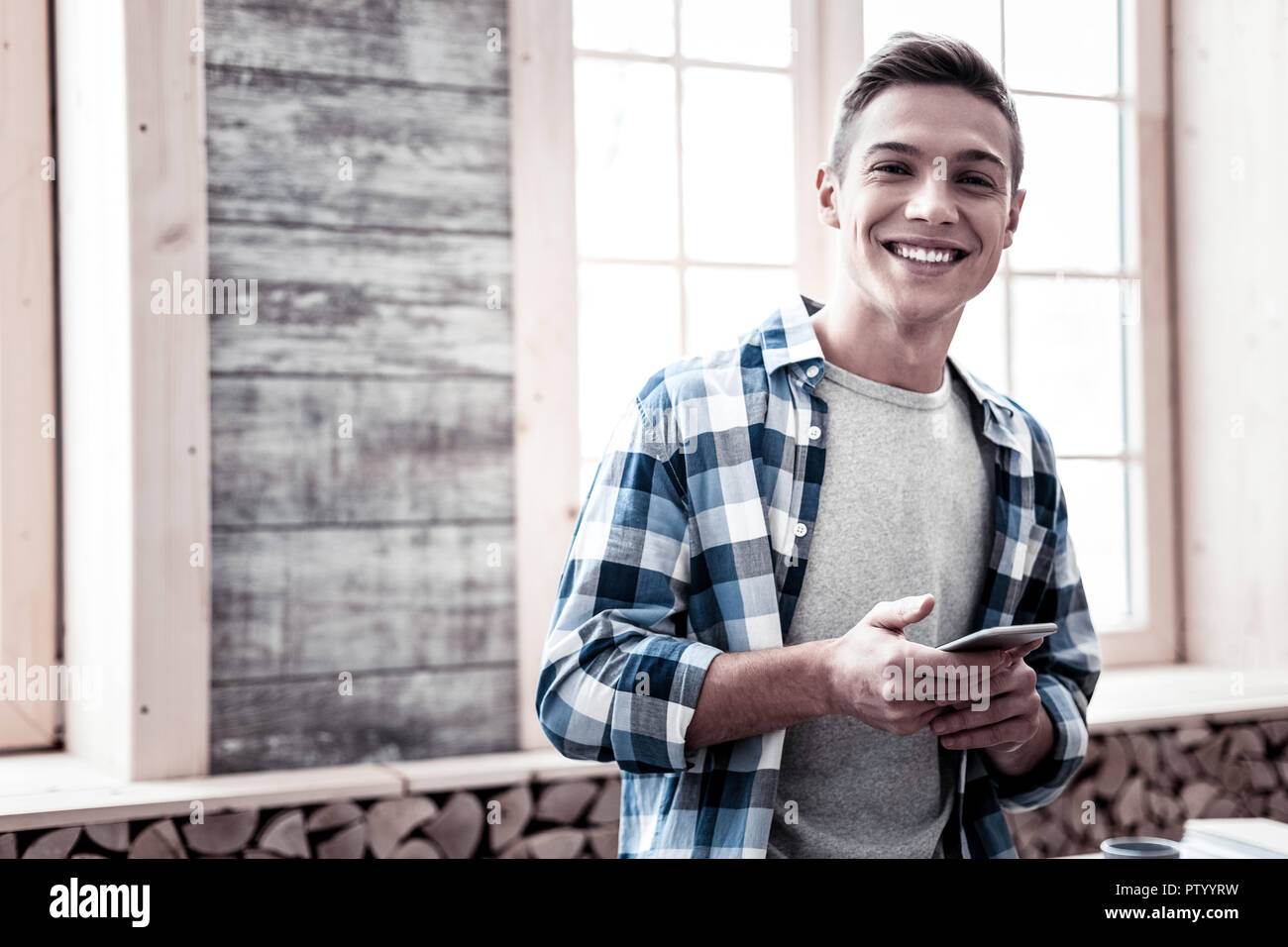 Neugierige junge Mann, der mit seinem Smartphone und glücklich lächelnd Stockfoto
